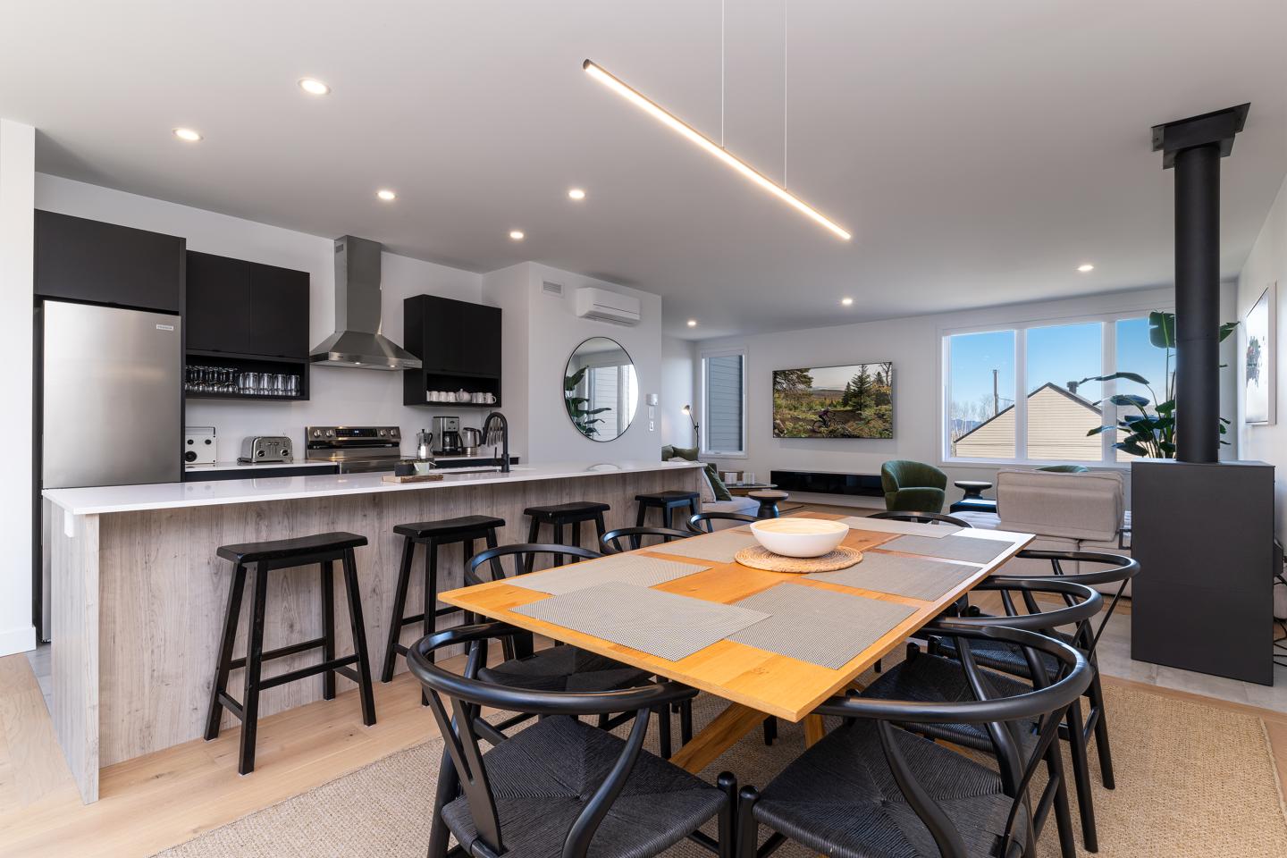 Cuisine moderne avec îlot, table à manger et fenêtre lumineuse.