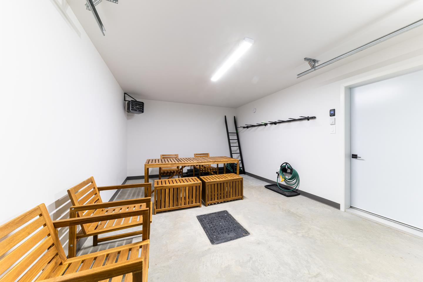 Salle blanche avec bancs en bois, échelle, et tuyau d'arrosage.