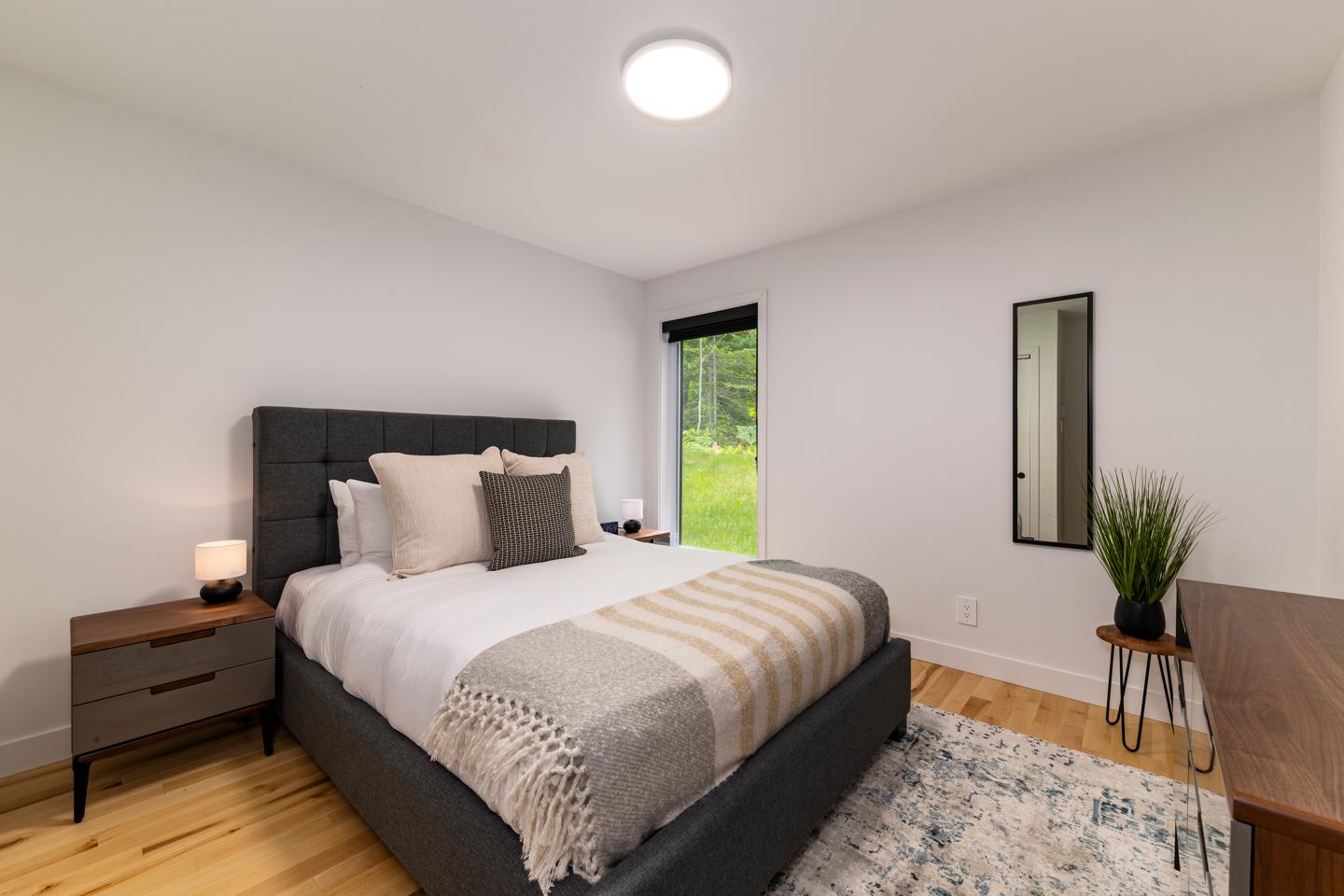 Chambre moderne avec lit double, tables de chevet et fenêtre.
