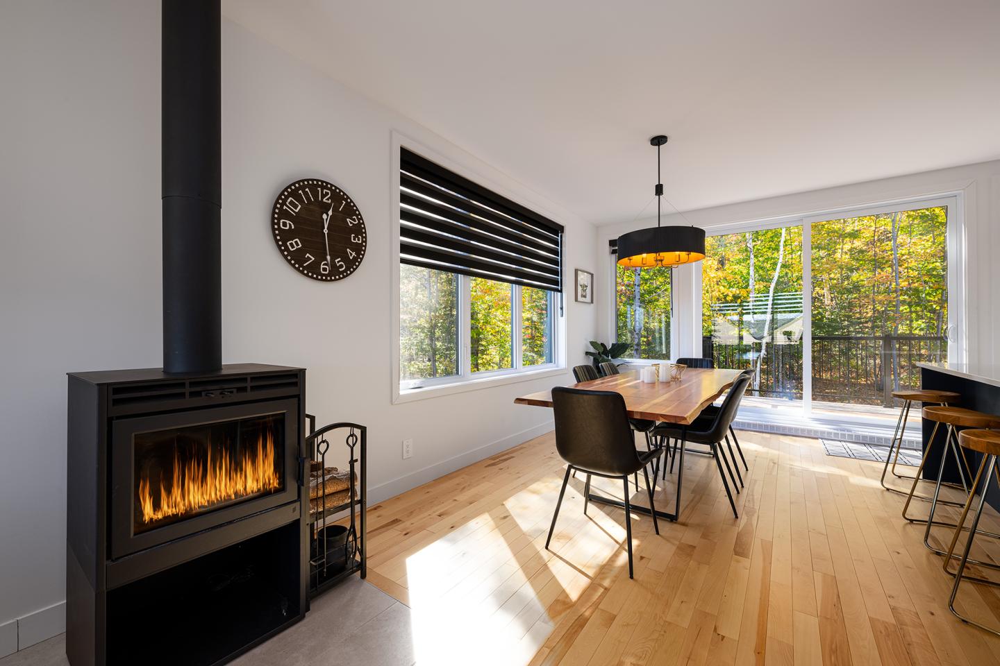 Salle à manger moderne avec cheminée et grande fenêtre sur jardin.