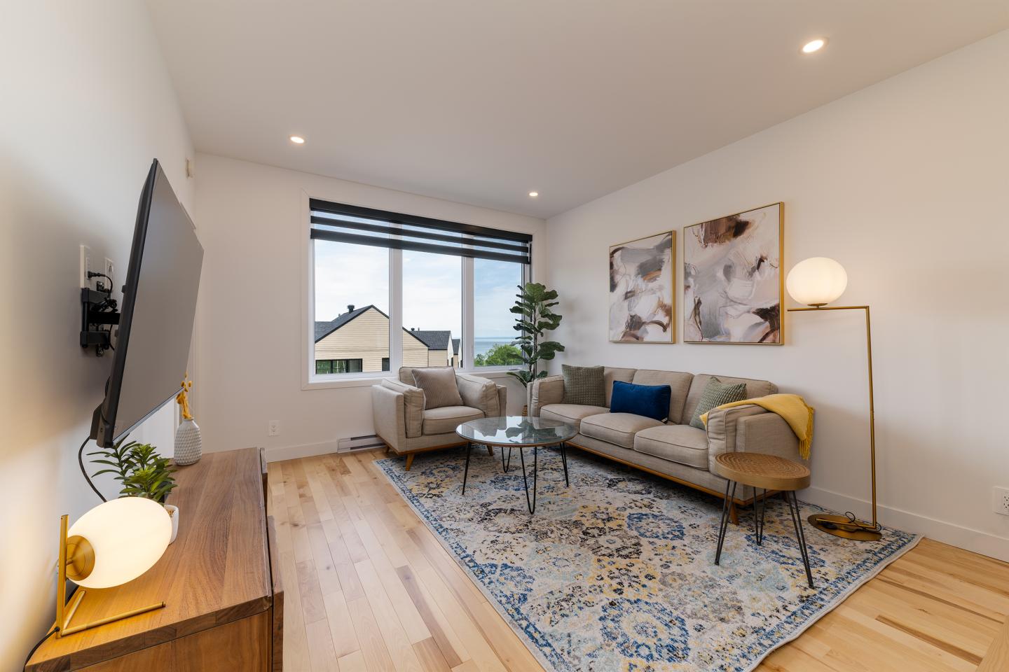 Salon moderne avec canapé, tapis coloré, et grande fenêtre.