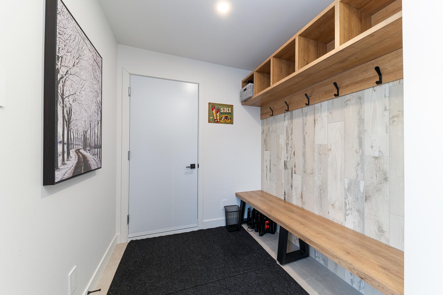 Couloir moderne avec banc en bois et crochets, tableau sur le mur.
