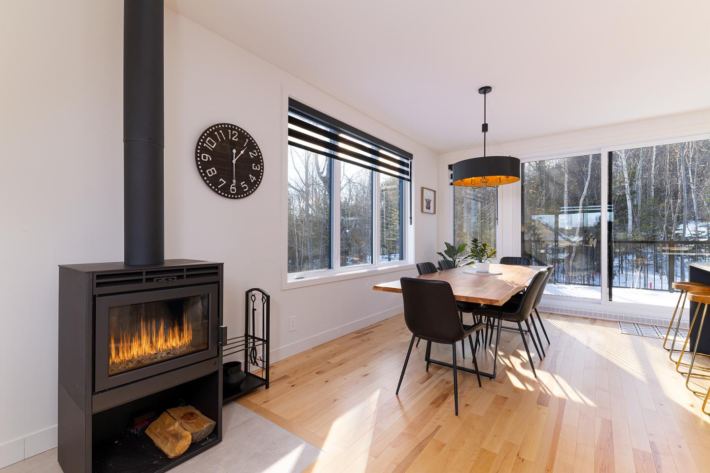 Salle à manger lumineuse avec cheminée moderne et table en bois.