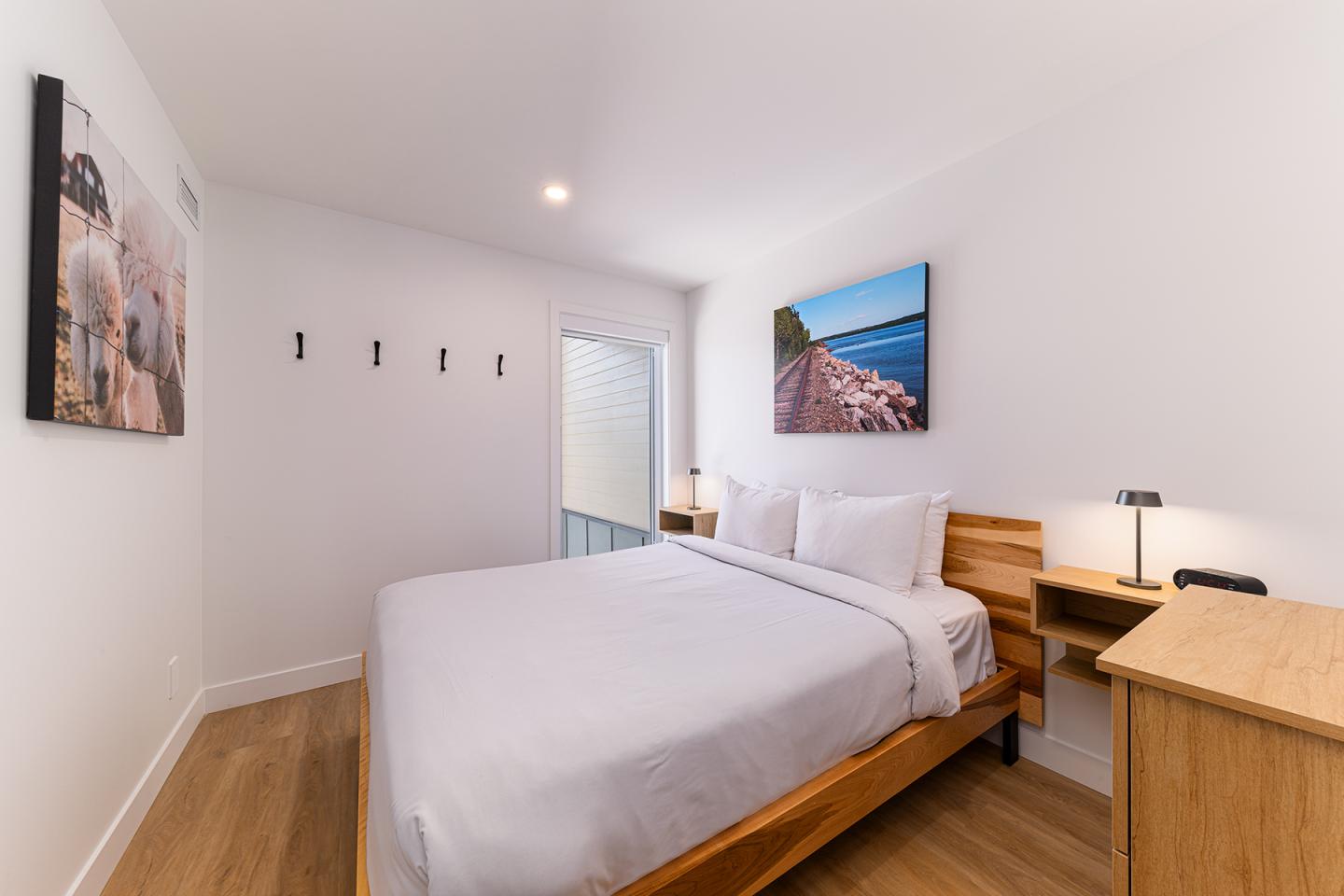 Chambre lumineuse avec lit double, tableaux et bureau en bois clair.