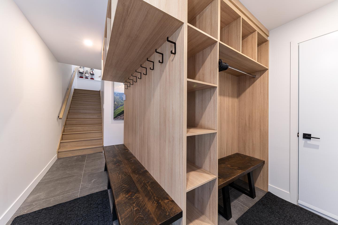 Couloir moderne avec bancs en bois et étagères, escalier au fond.