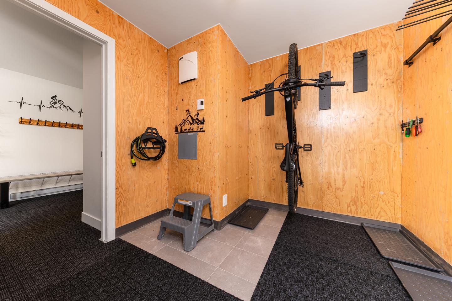 Mur de rangement en bois avec vélo suspendu et supports, pièce organisée.