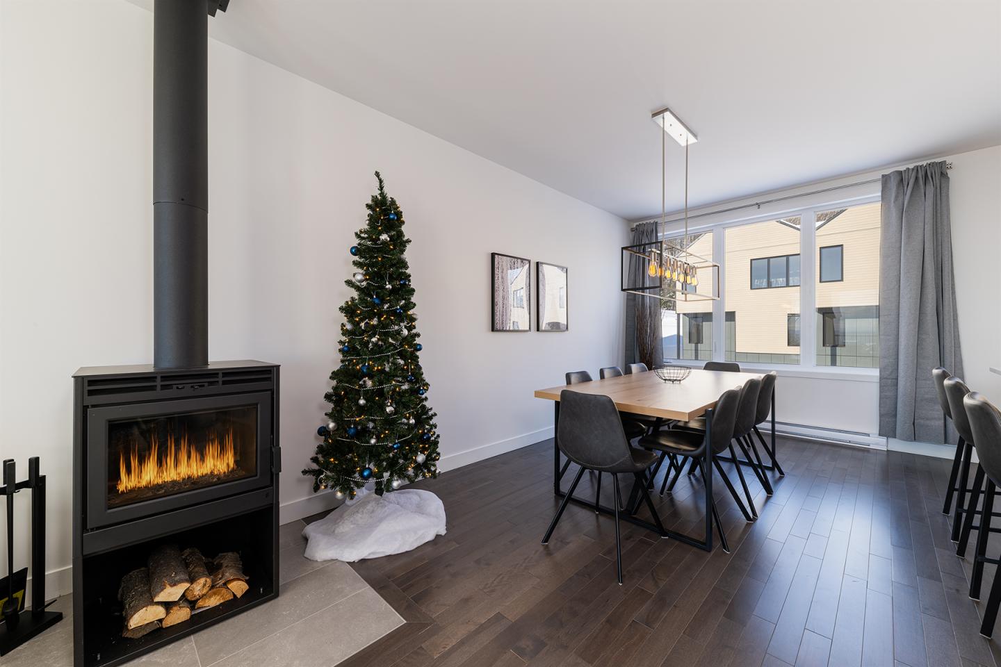 Salle à manger moderne avec cheminée, table en bois et sapin de Noël.