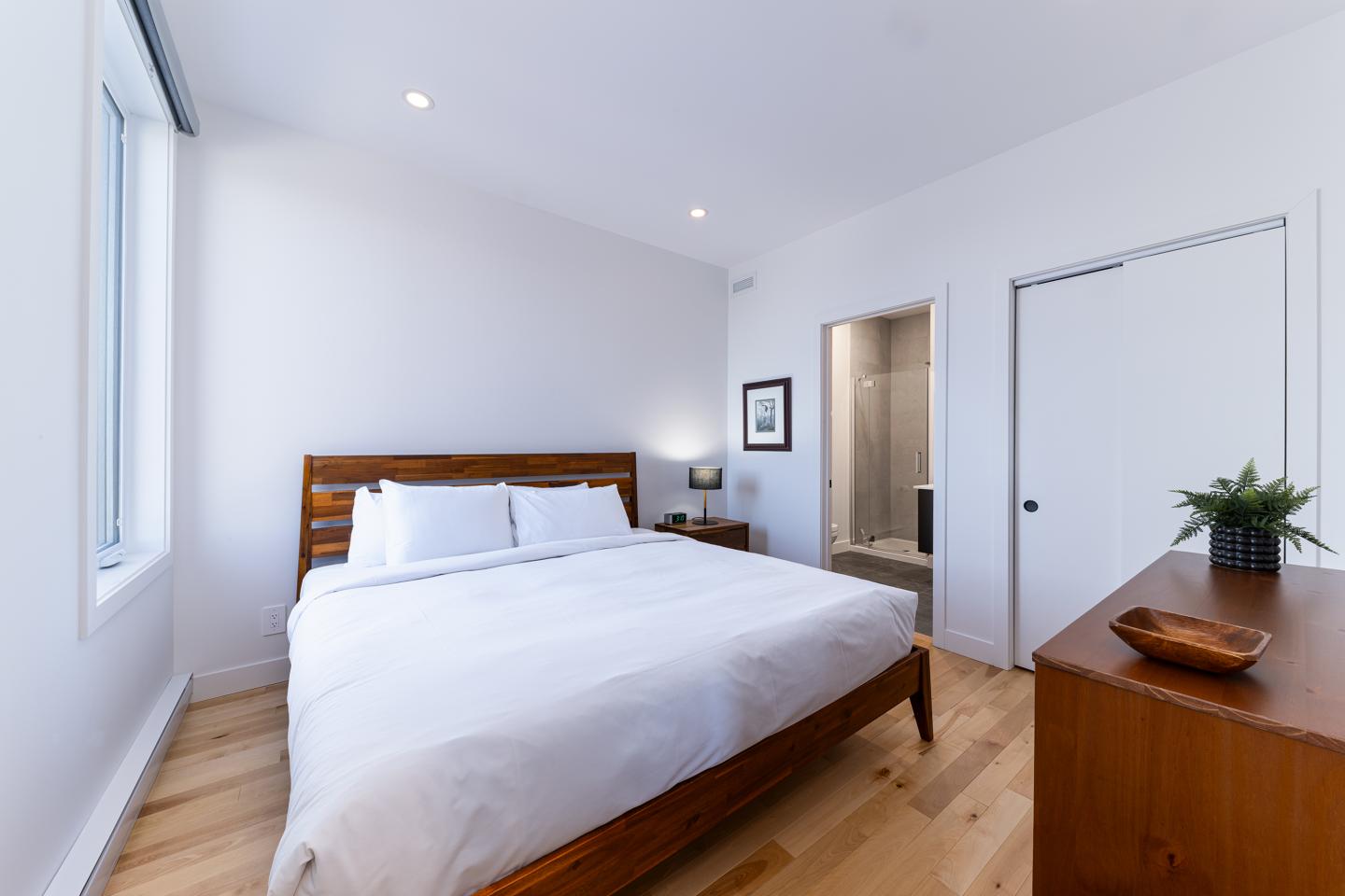 Chambre moderne avec lit double, parquet et éclairage doux.