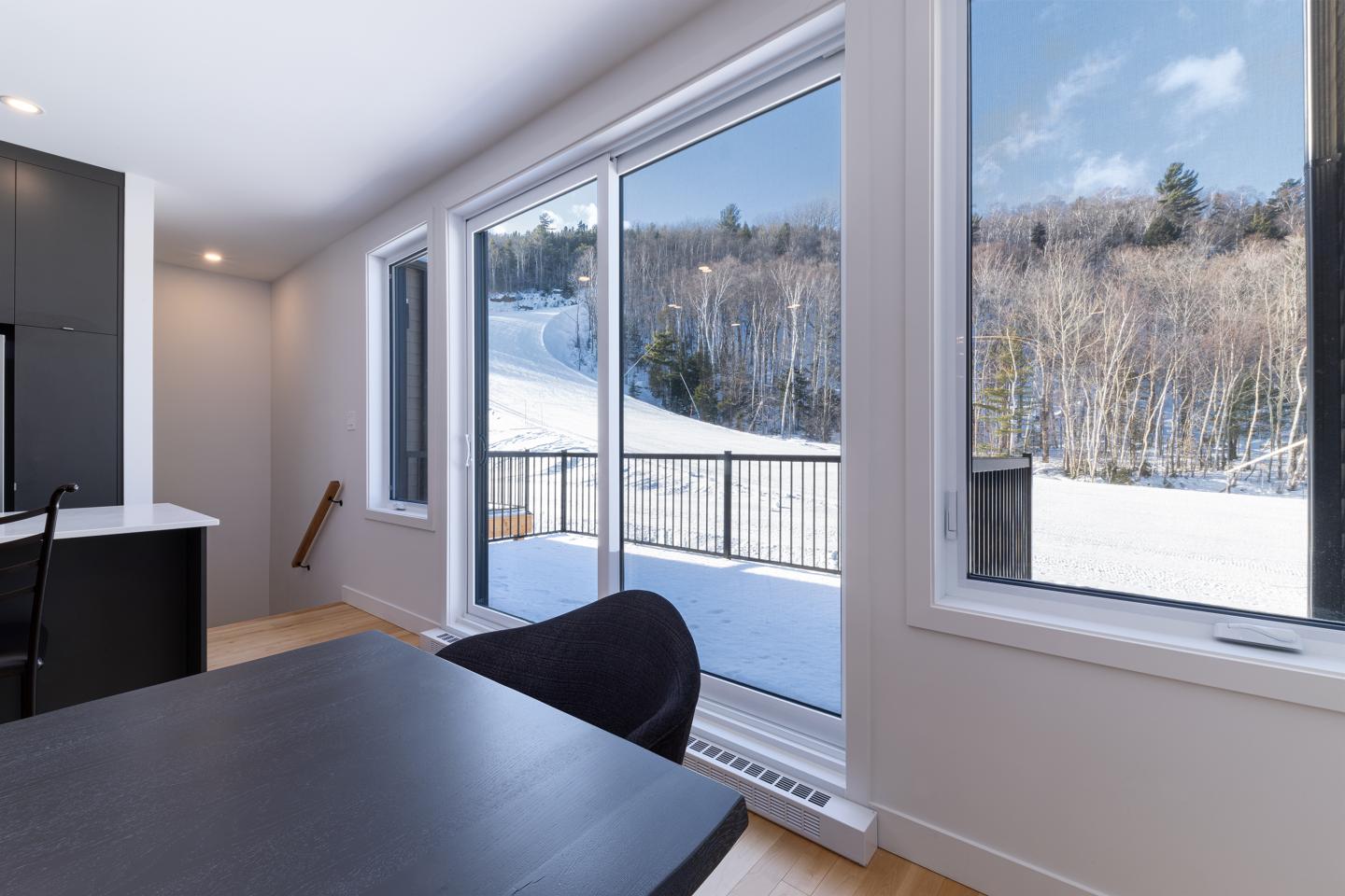 Vue hivernale depuis une salle à manger moderne avec de grandes fenêtres.