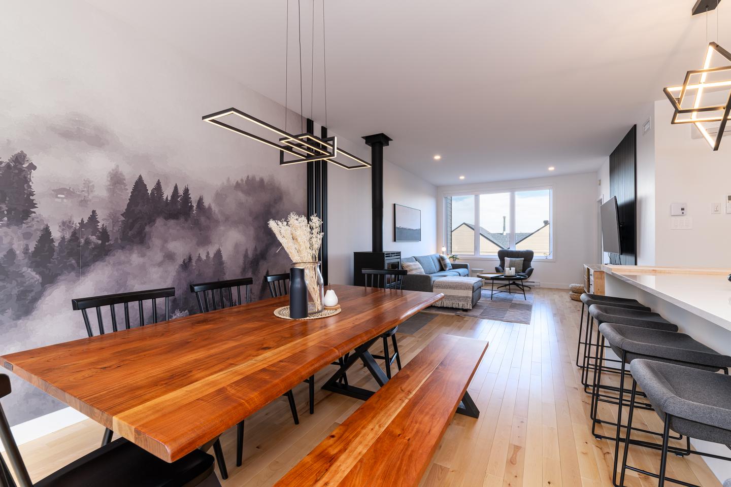Salle à manger moderne avec table en bois, chaises noires et fresque murale.