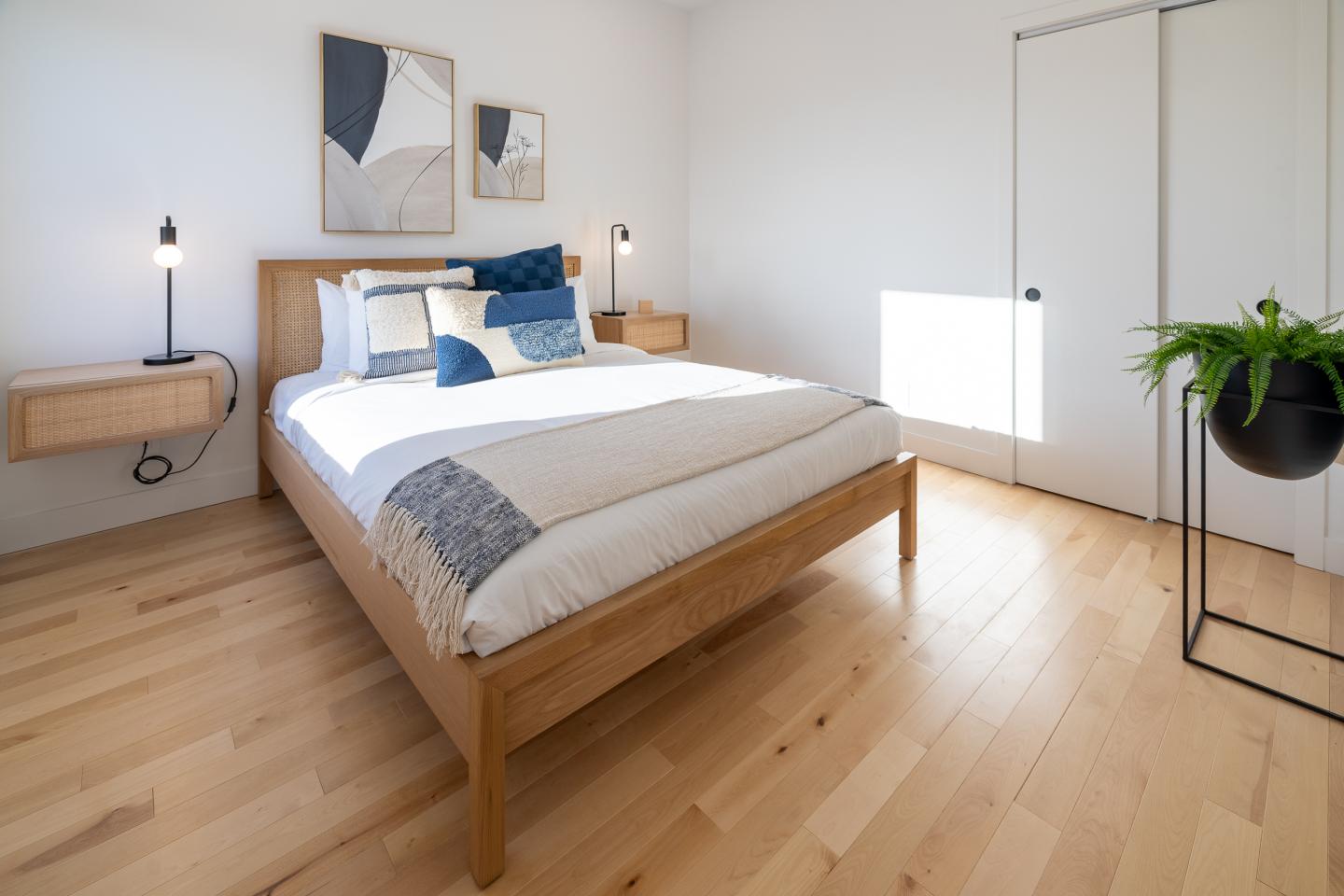 Chambre minimaliste avec lit en bois, parquet clair et décoration moderne.