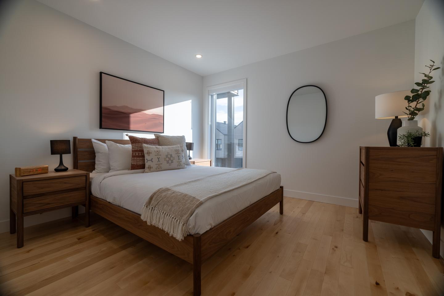 Chambre moderne avec lit en bois, décoration minimaliste et lumière naturelle.