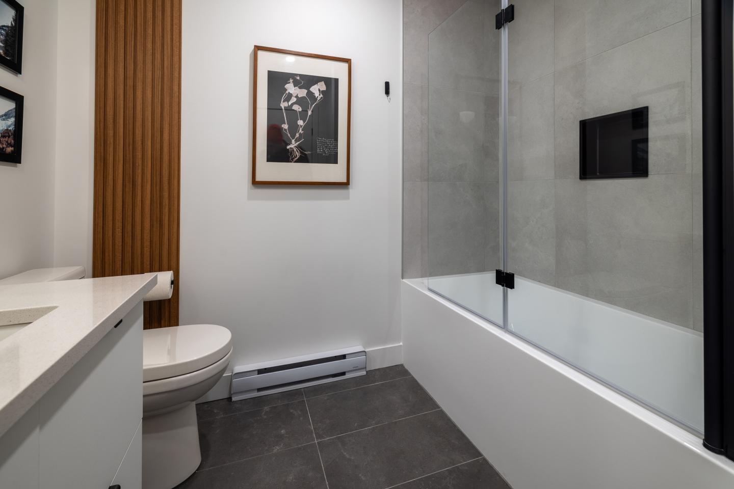 Salle de bain moderne avec baignoire et cadre mural noir et blanc.