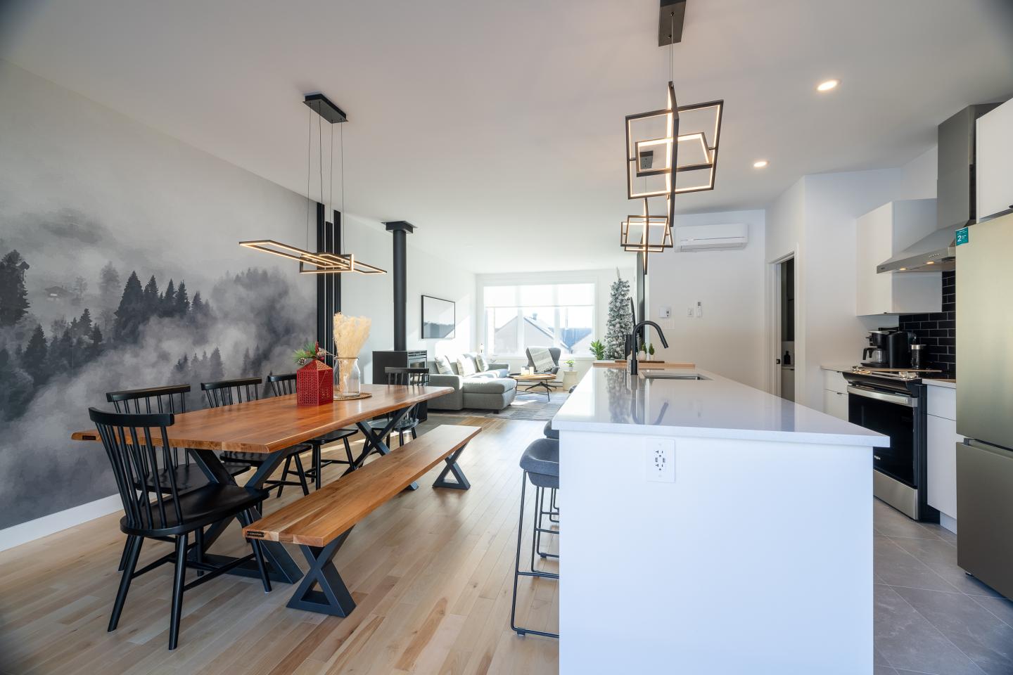Salle à manger moderne avec table en bois, chaises noires et cuisine ouverte claire.