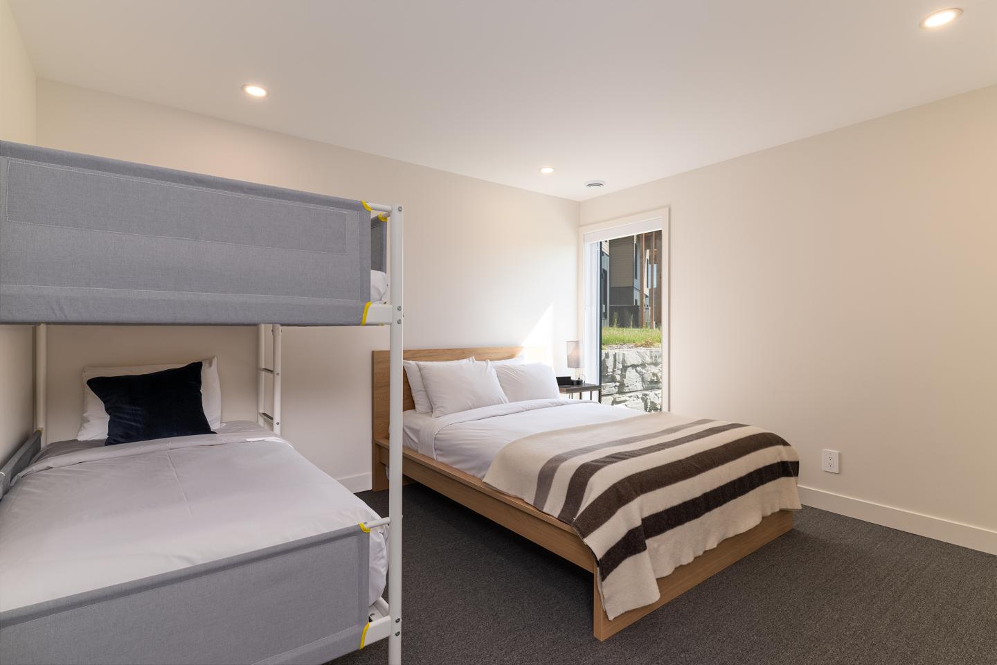 Chambre moderne avec lit double, lit superposé et fenêtre.