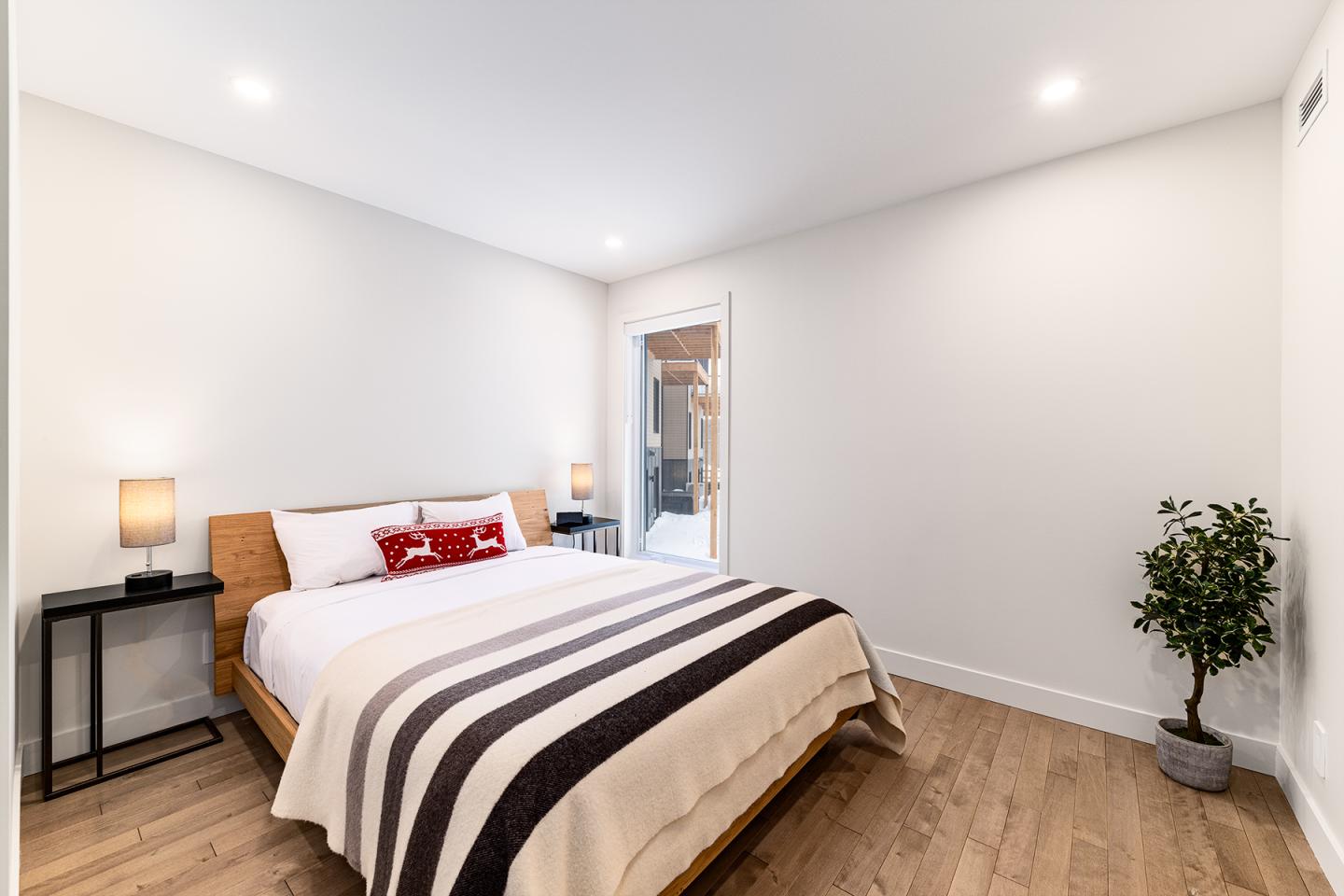 Chambre moderne avec lit, lampes de chevet, et plante.