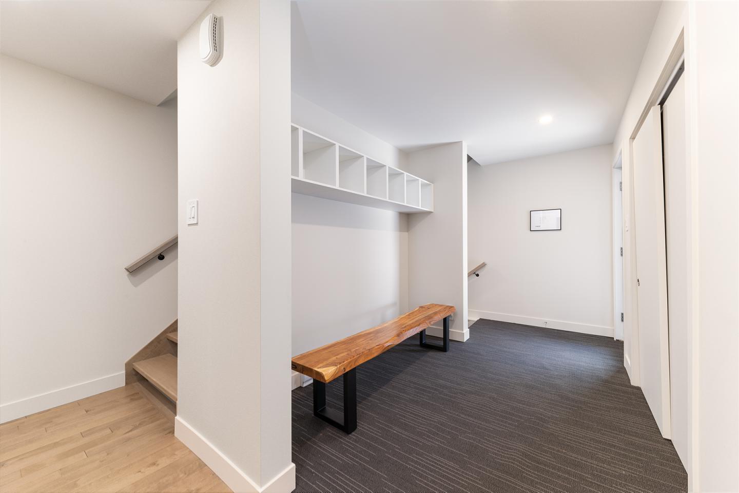 Couloir moderne avec banc en bois, escalier à gauche.