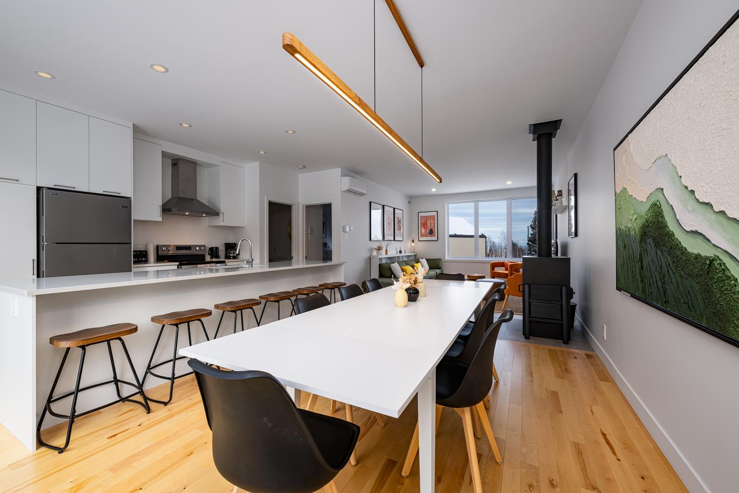 Cuisine moderne avec îlot central, table à manger et poêle noir.