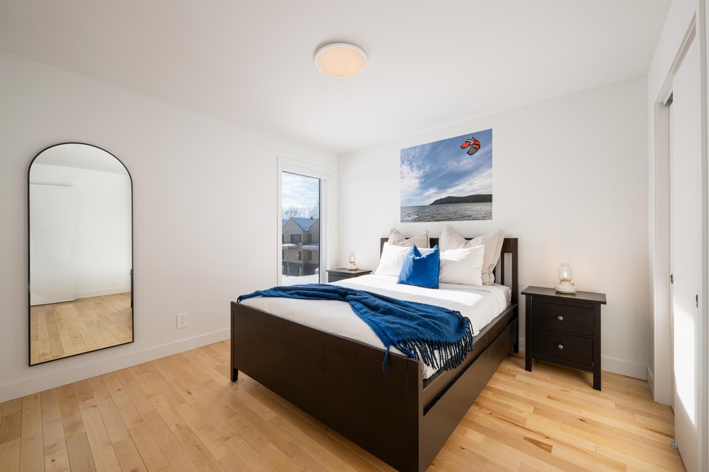 Chambre lumineuse avec lit double, miroir et tableau.