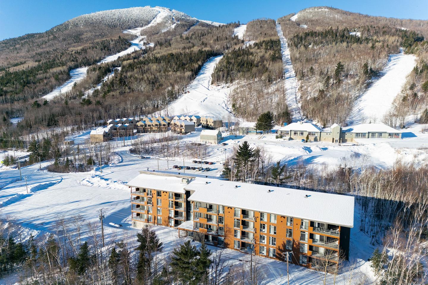 Station de ski enneigée avec pistes et bâtiments au pied de la montagne.