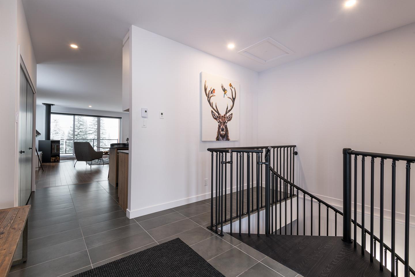 Entrée moderne avec tableau de cerf et escalier noir.