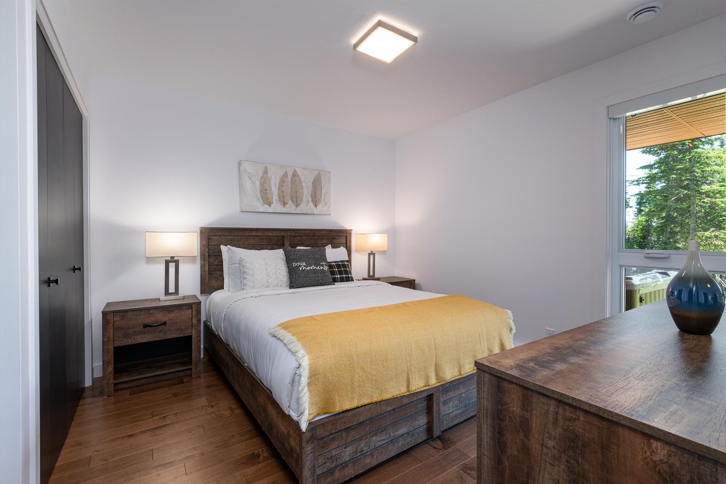 Chambre moderne avec lit double, lampe de chevet allumée et fenêtre ouverte.