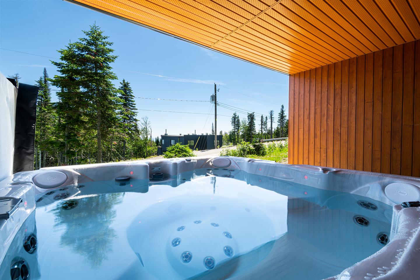 Spa extérieur avec ciel bleu et forêt en arrière-plan.