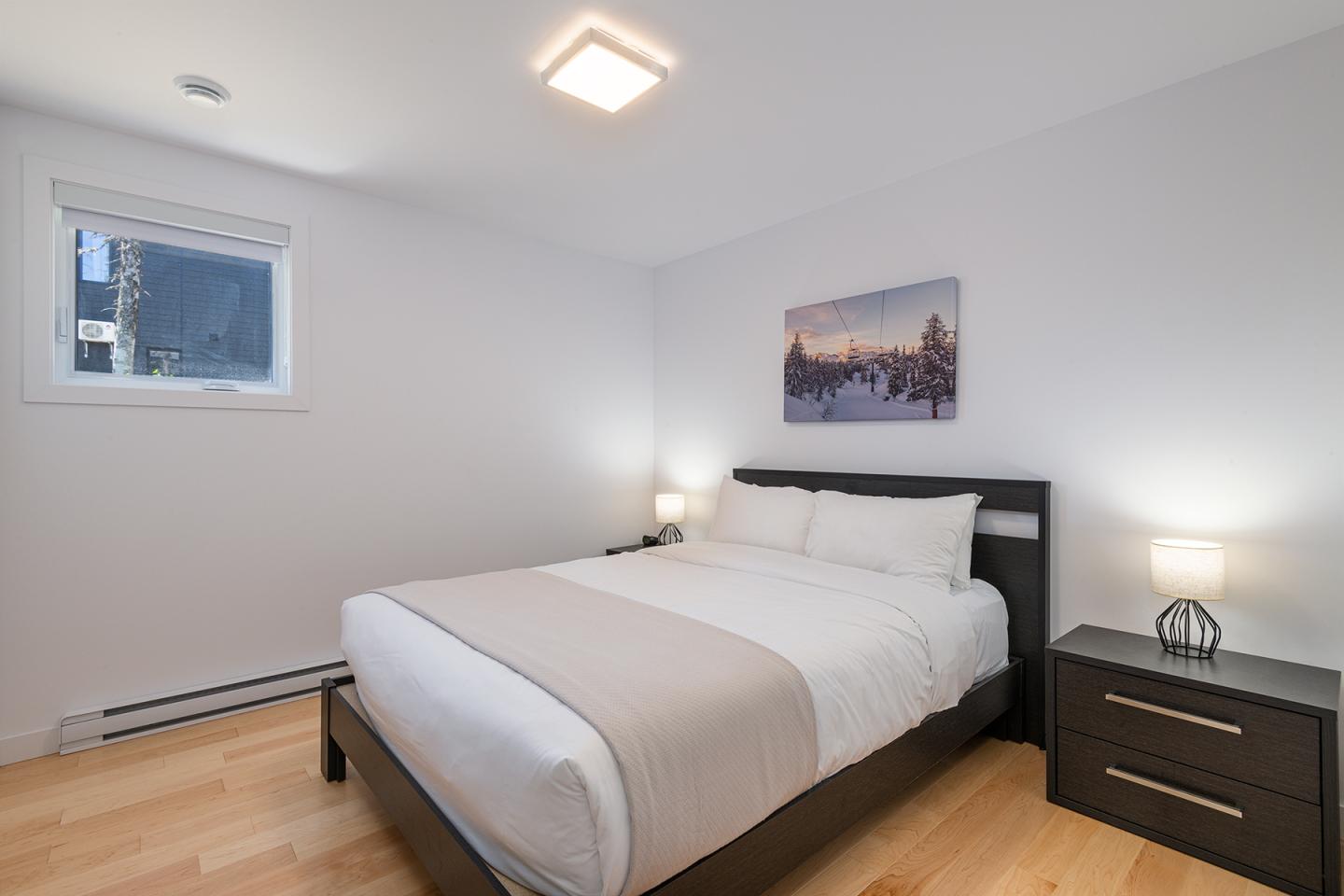Chambre claire avec lit double, deux tables de nuit et un tableau sur le mur.