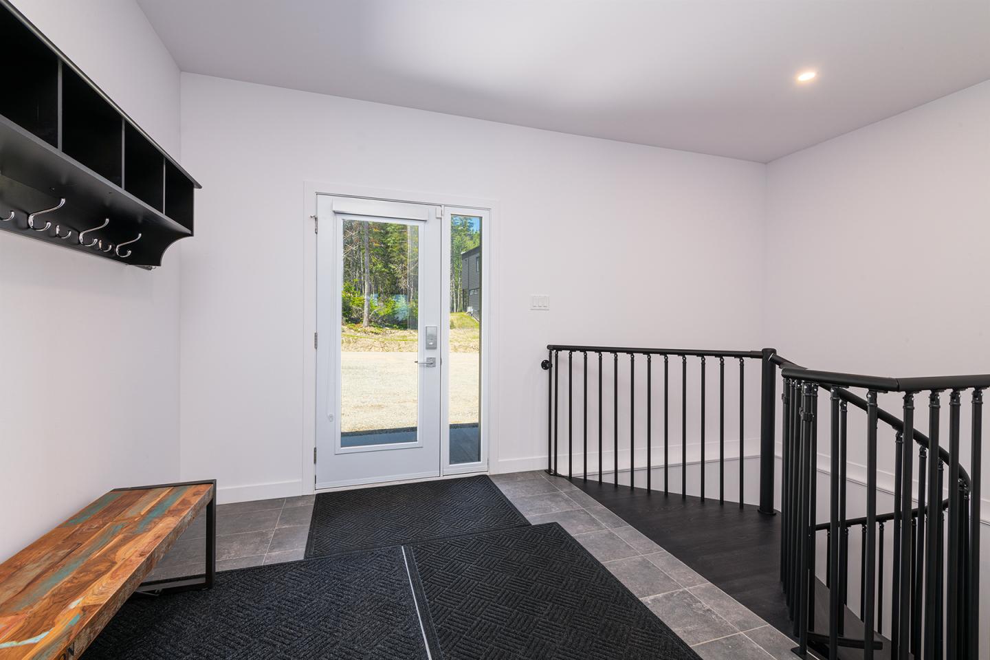 Entrée lumineuse avec escalier en colimaçon et banc en bois.