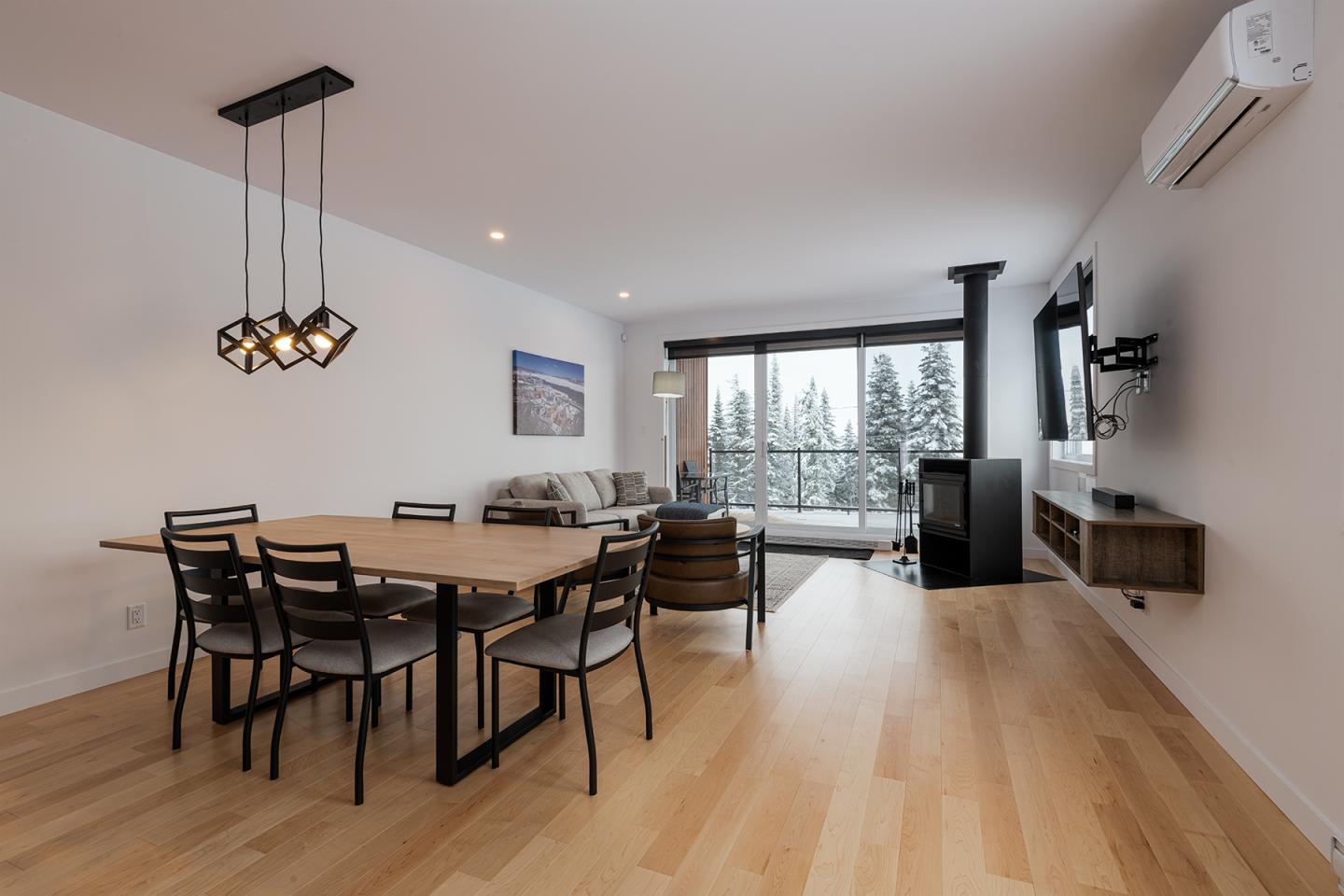 Salle à manger moderne avec table en bois et vue sur un salon lumineux.