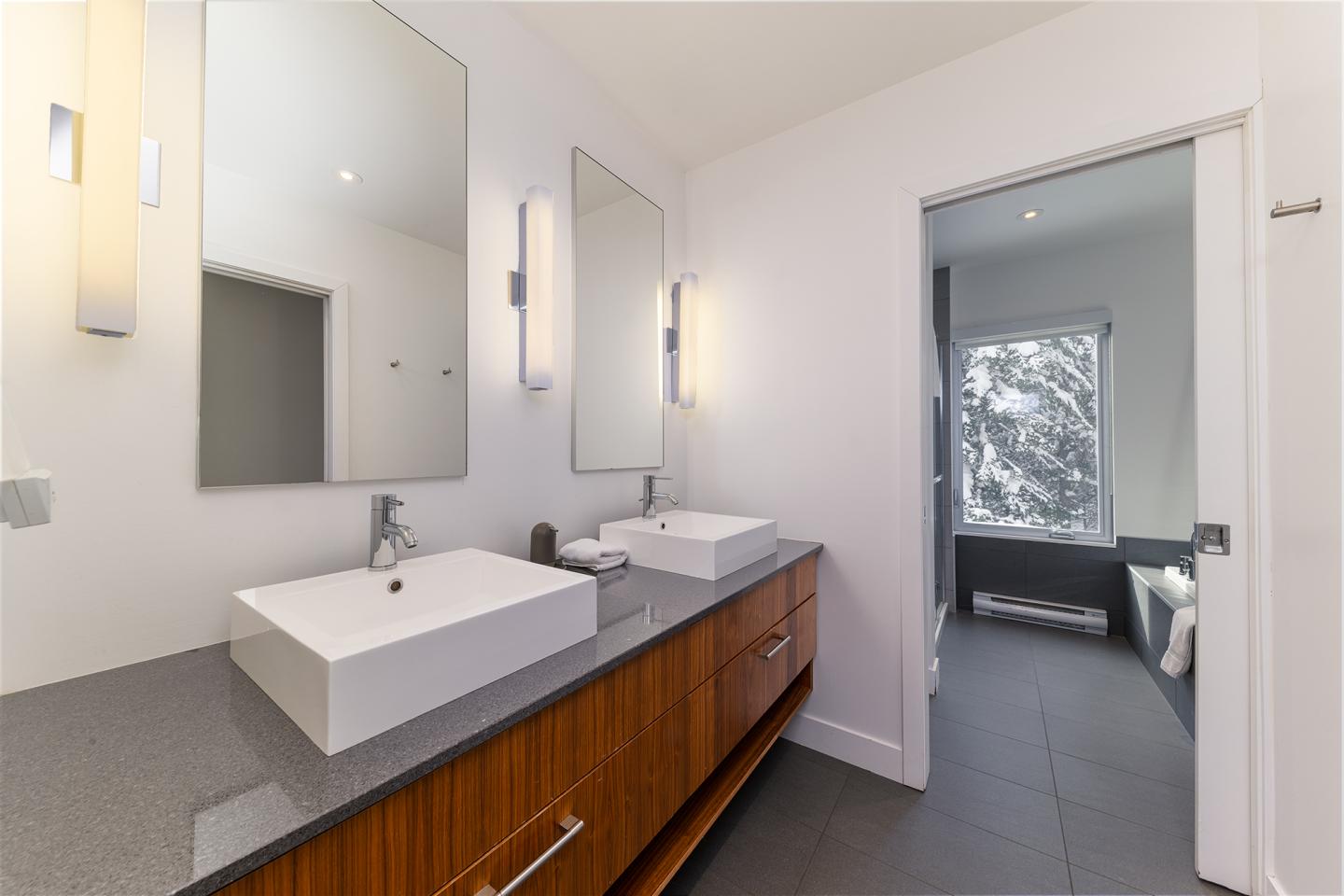 Salle de bain moderne avec double vasque et miroir, lumière naturelle.
