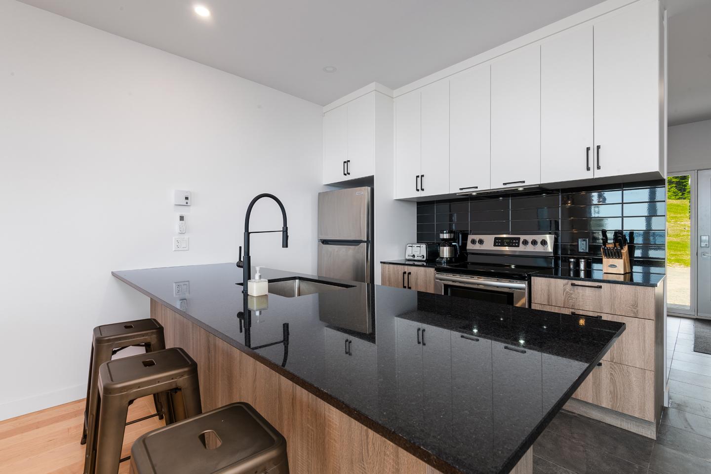 Cuisine moderne avec îlot central, comptoir noir et électroménager en inox.