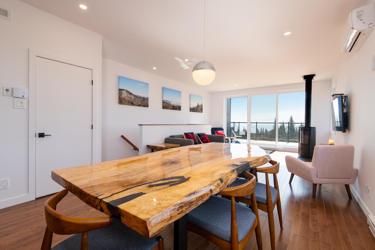 Salle à manger moderne avec table en bois, baies vitrées et décoration épurée.