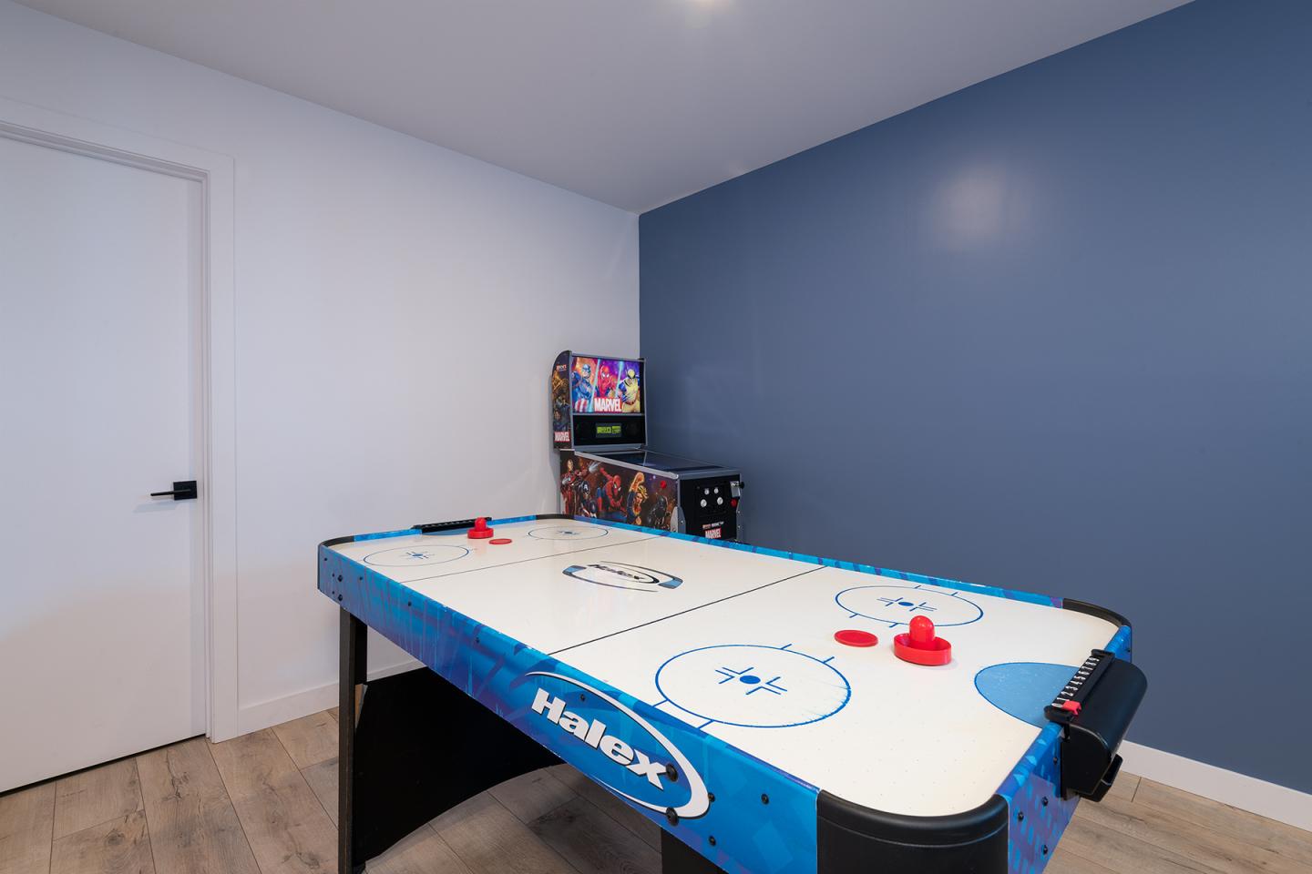 Salle de jeux avec table de air hockey et borne d'arcade.