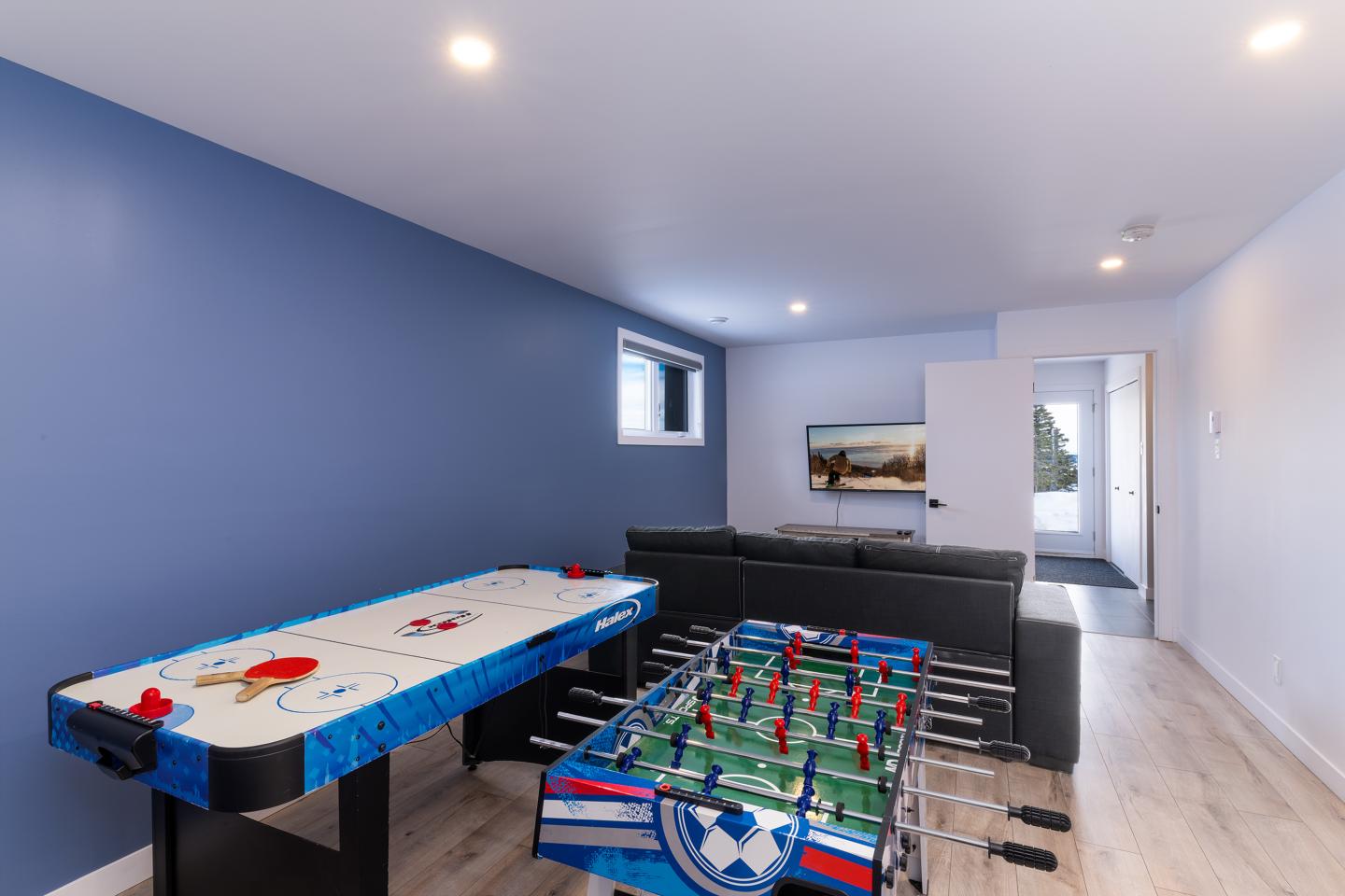 Salle de jeux avec hockey sur table, baby-foot et télé.
