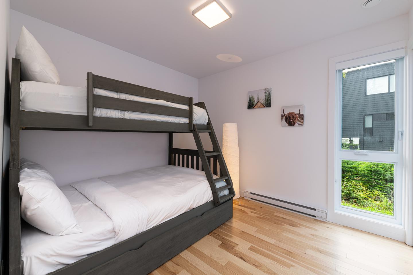 Chambre avec lit superposé, parquet clair, grande fenêtre.