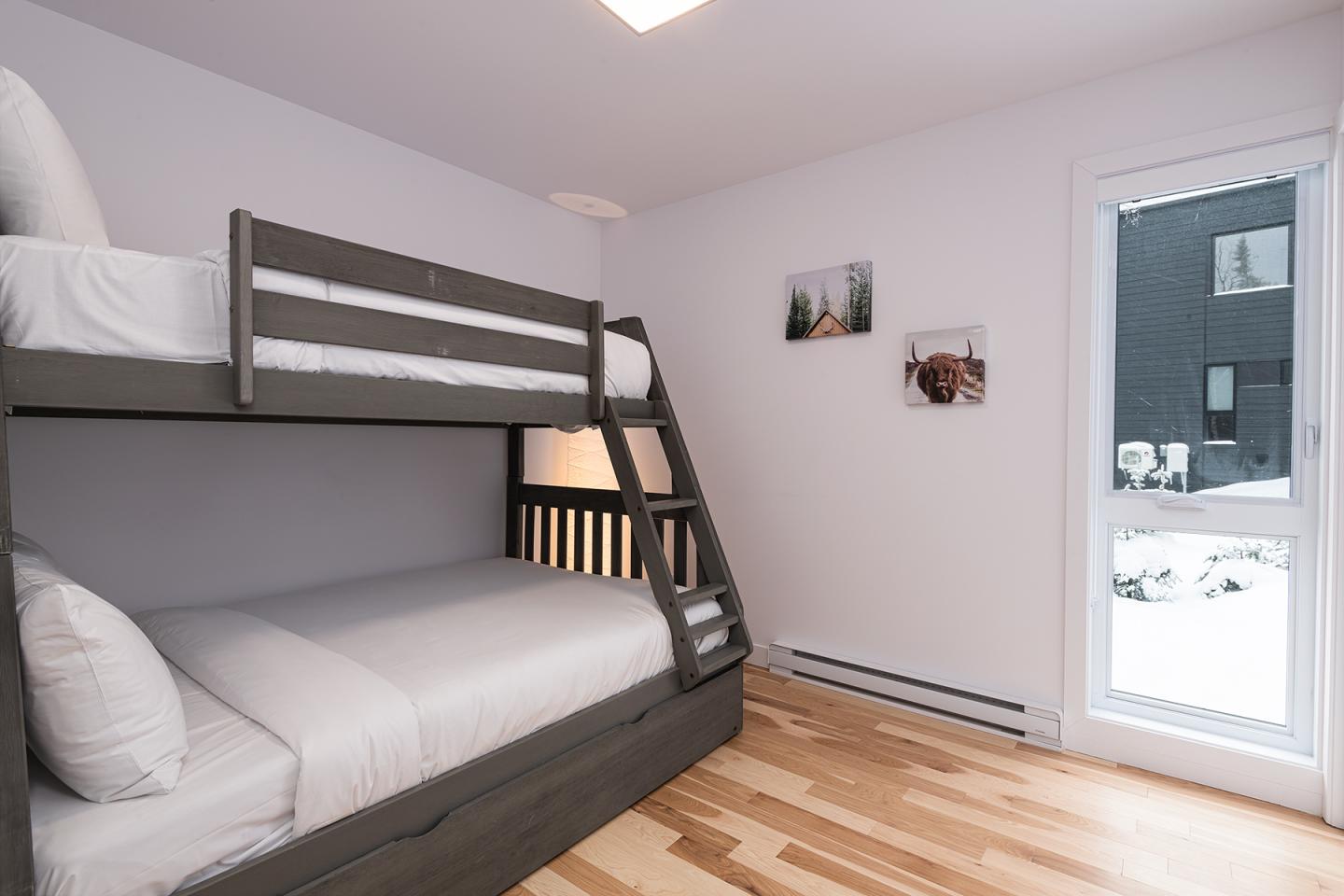 Lit superposé moderne dans une chambre blanche avec parquet et photos murales.