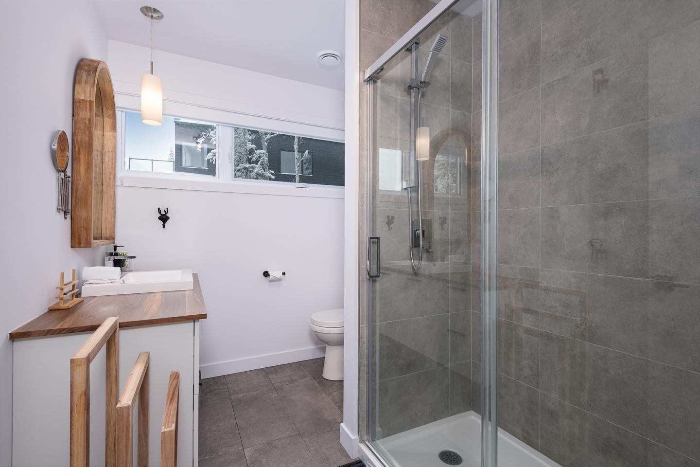 Salle de bain moderne avec cabine de douche vitrée et lavabo en bois clair.