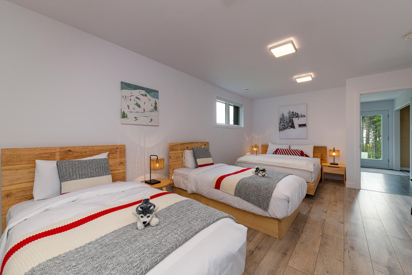 Chambre moderne avec deux lits, plancher en bois, décoration minimaliste.