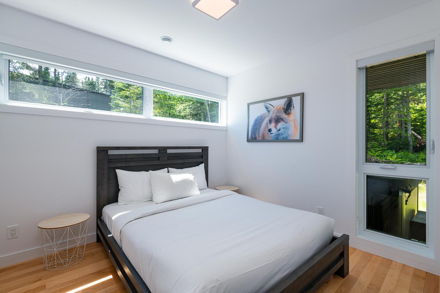 Chambre moderne avec lit double, grandes fenêtres, lumière naturelle.