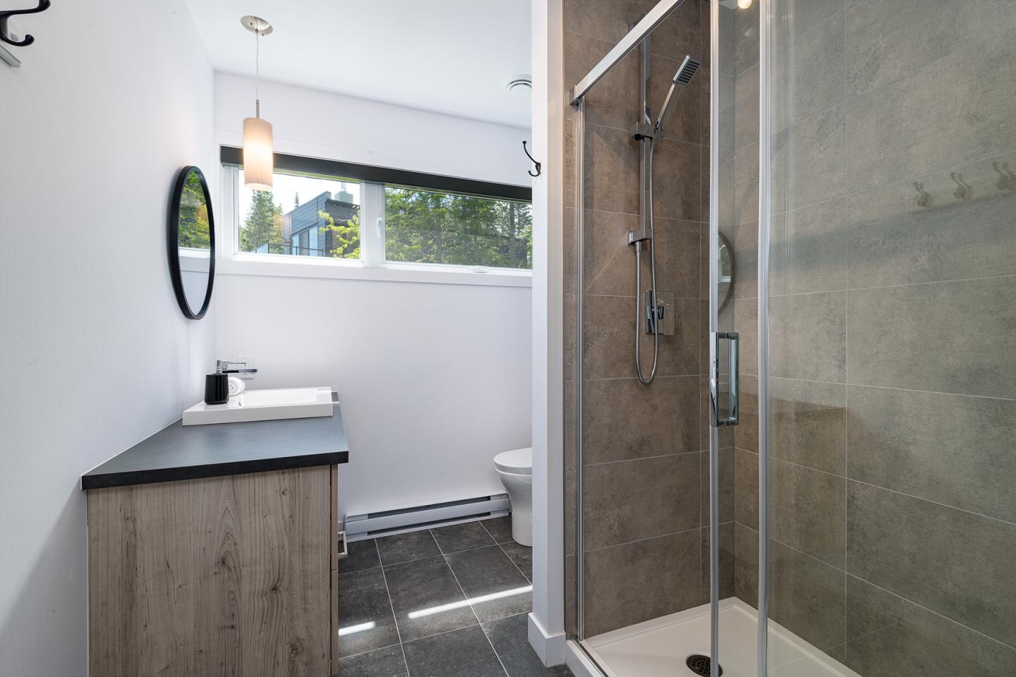 Salle de bain moderne avec douche à paroi vitrée et lavabo simple.