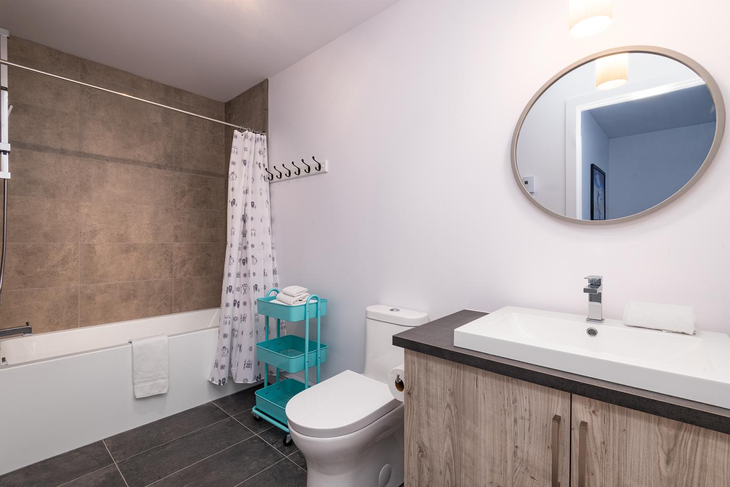 Salle de bain moderne avec baignoire, lavabo et étagère turquoise.