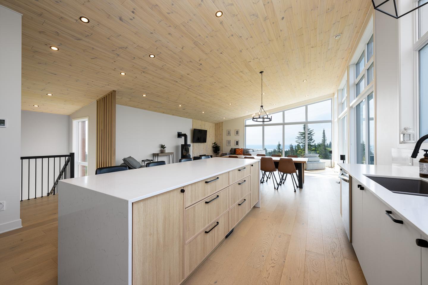Cuisine moderne spacieuse avec îlot central, grandes fenêtres et vue extérieure.