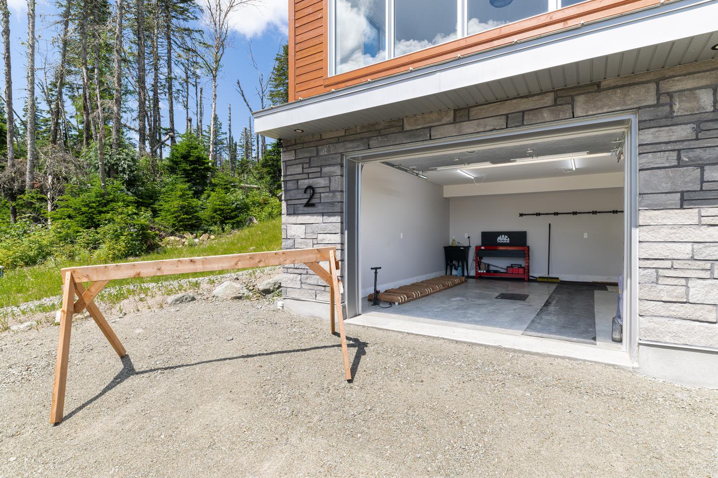 Garage ouvert avec établi en bois à l'extérieur, outils à l'intérieur.
