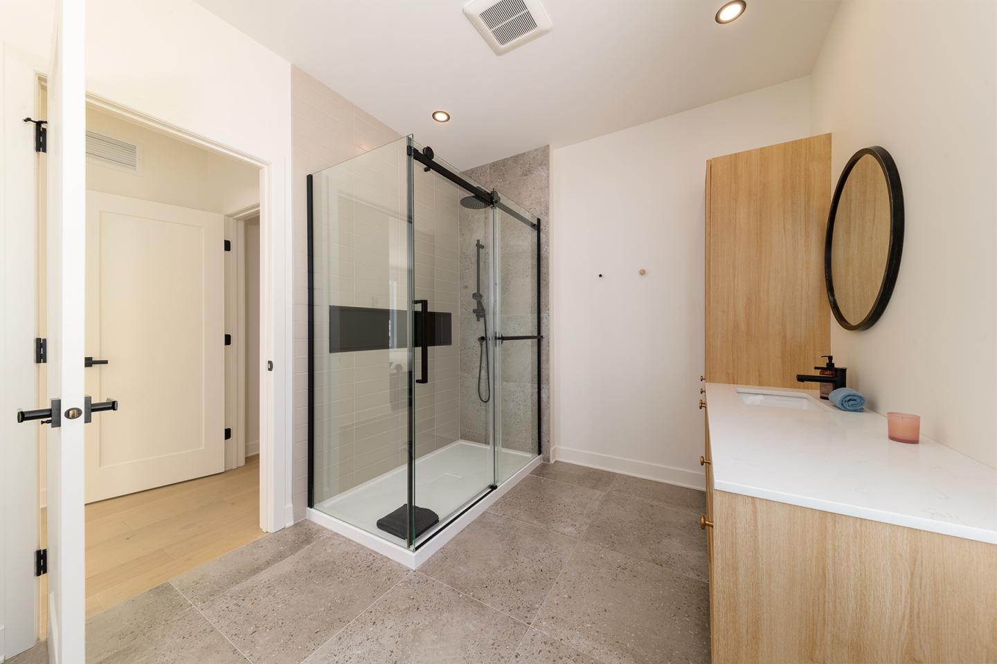 Salle de bain moderne avec douche vitrée et meuble en bois.