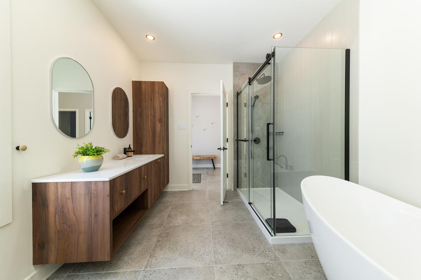 Salle de bain moderne avec douche vitrée et baignoire blanche.