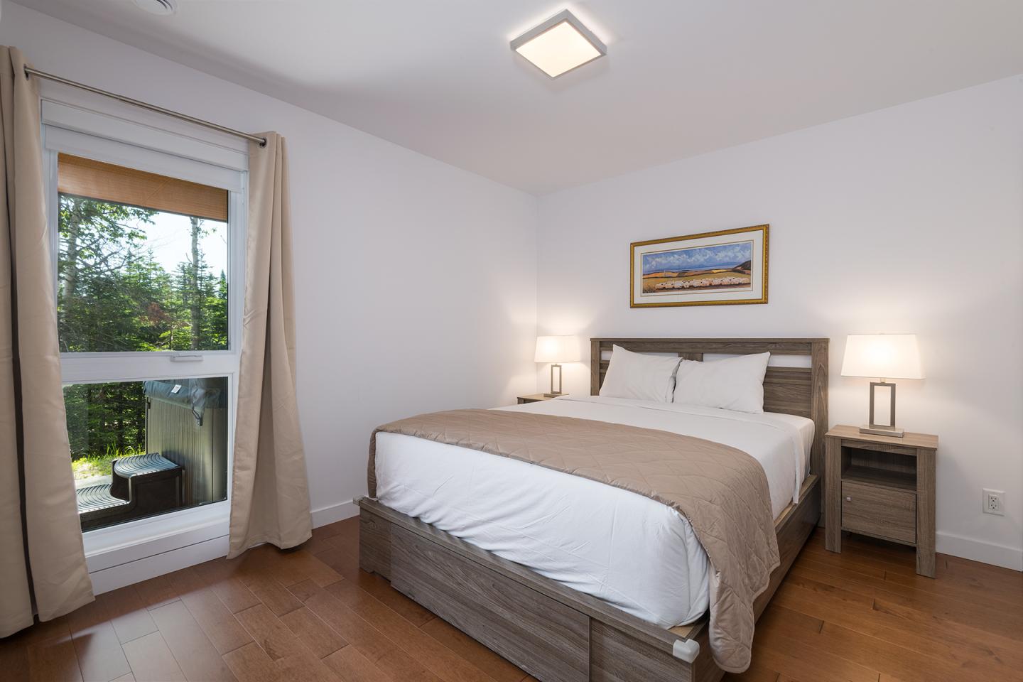 Chambre lumineuse avec lit double et fenêtre donnant sur la verdure.