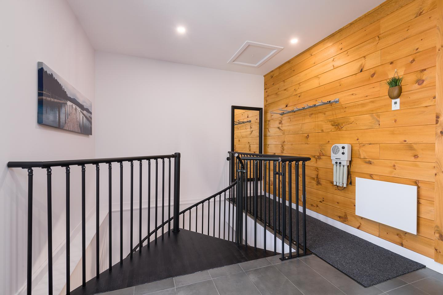 Escalier intérieur moderne avec mur en bois et rampe noire.