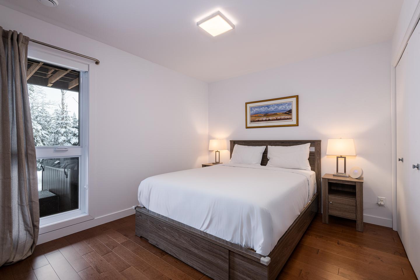Chambre lumineuse avec lit double, deux lampes et une fenêtre.