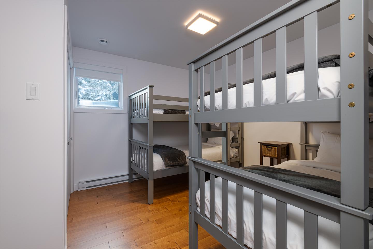 Chambre avec lits superposés gris sur parquet clair, lumière naturelle.